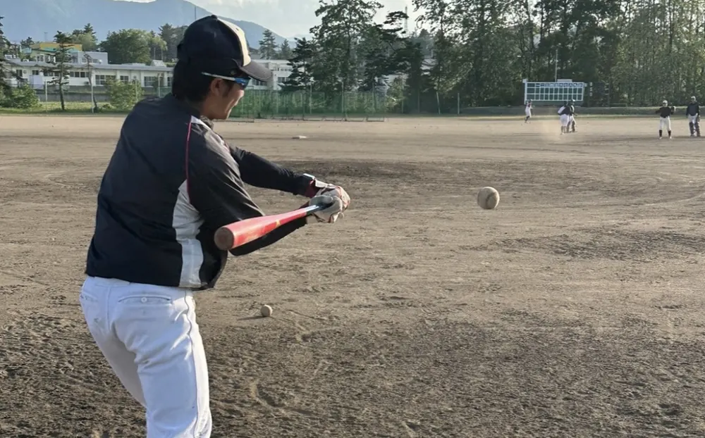 グラウンドで部員にノックを打つ山内開登
